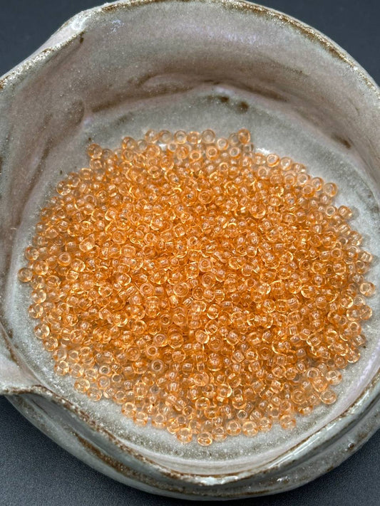 Close-up of small orange beads in a container with a textured surface.
