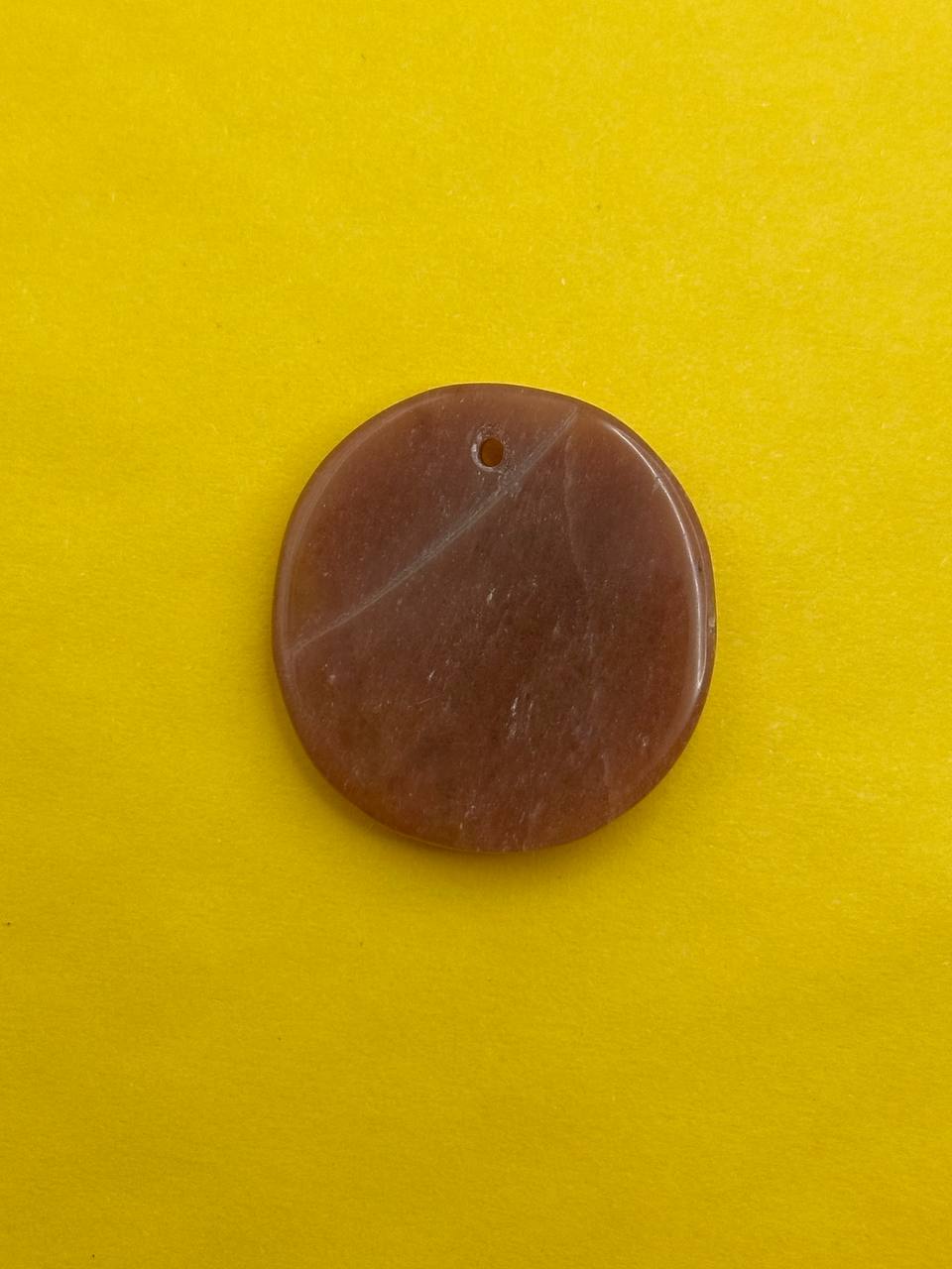 Brown circular stone with a hole on a yellow background