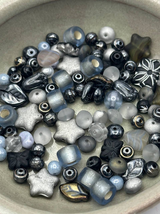 Assorted glass beads in various shapes and colors on a beige surface