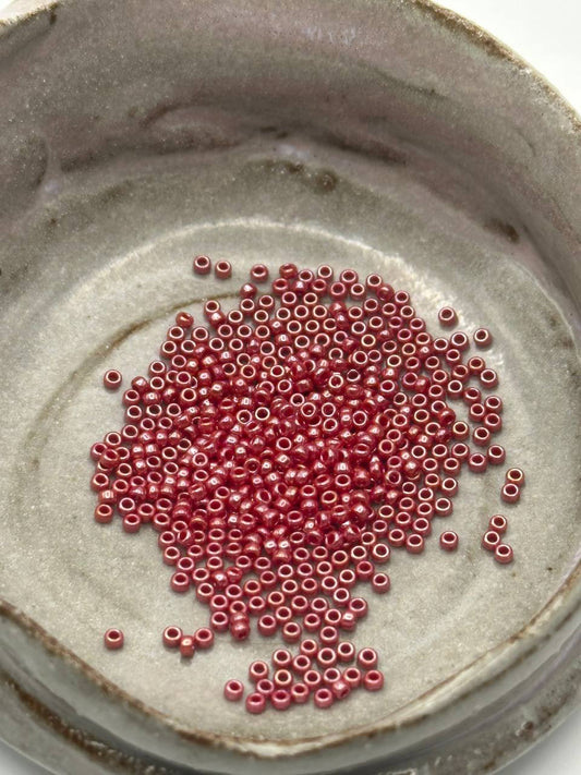 Small pink beads scattered on a textured gray surface