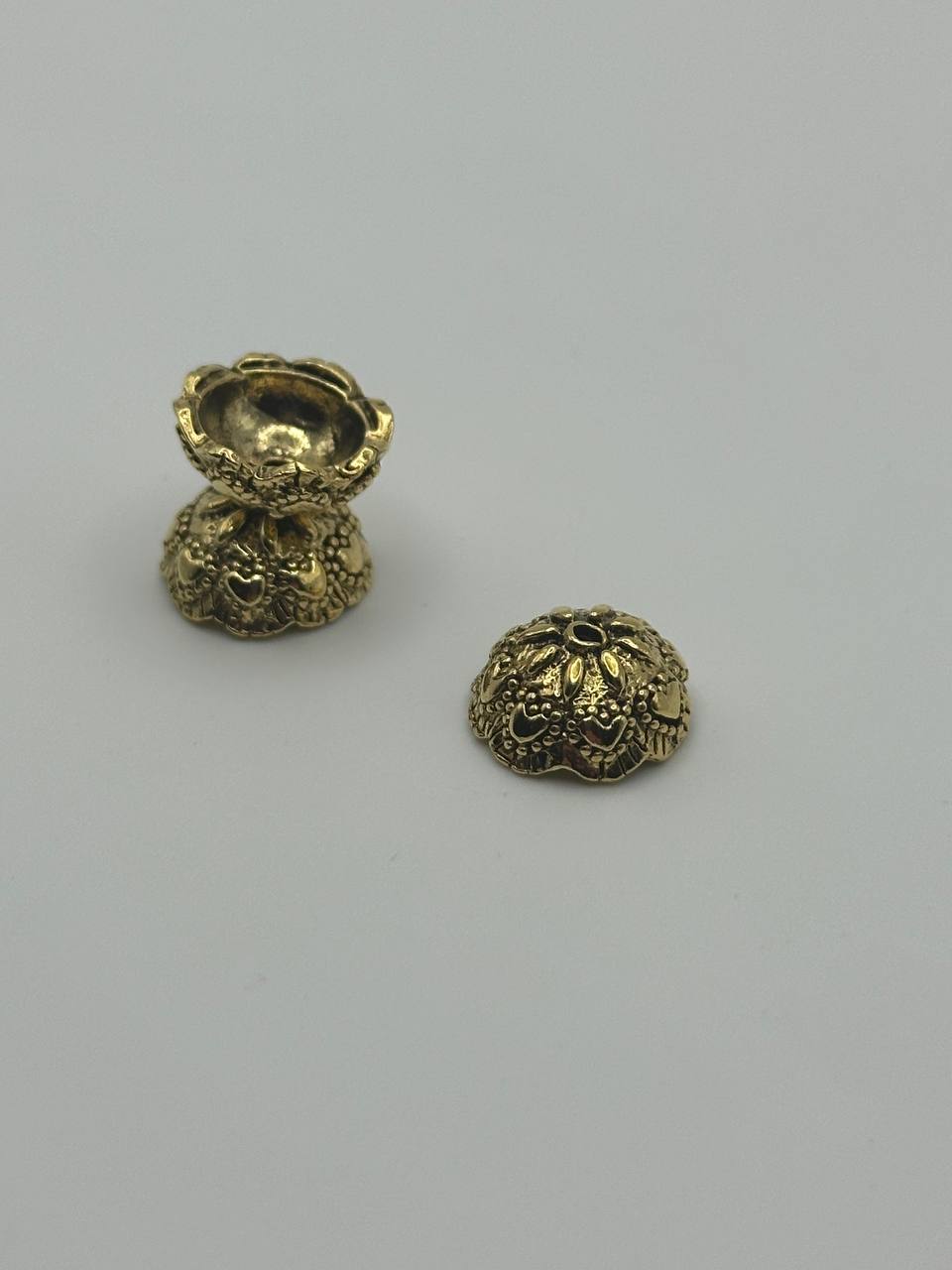 Three gold beads with intricate designs on a light gray background