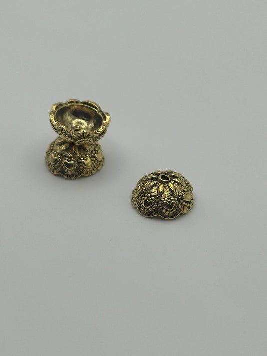 Three gold beads with intricate designs on a light gray background
