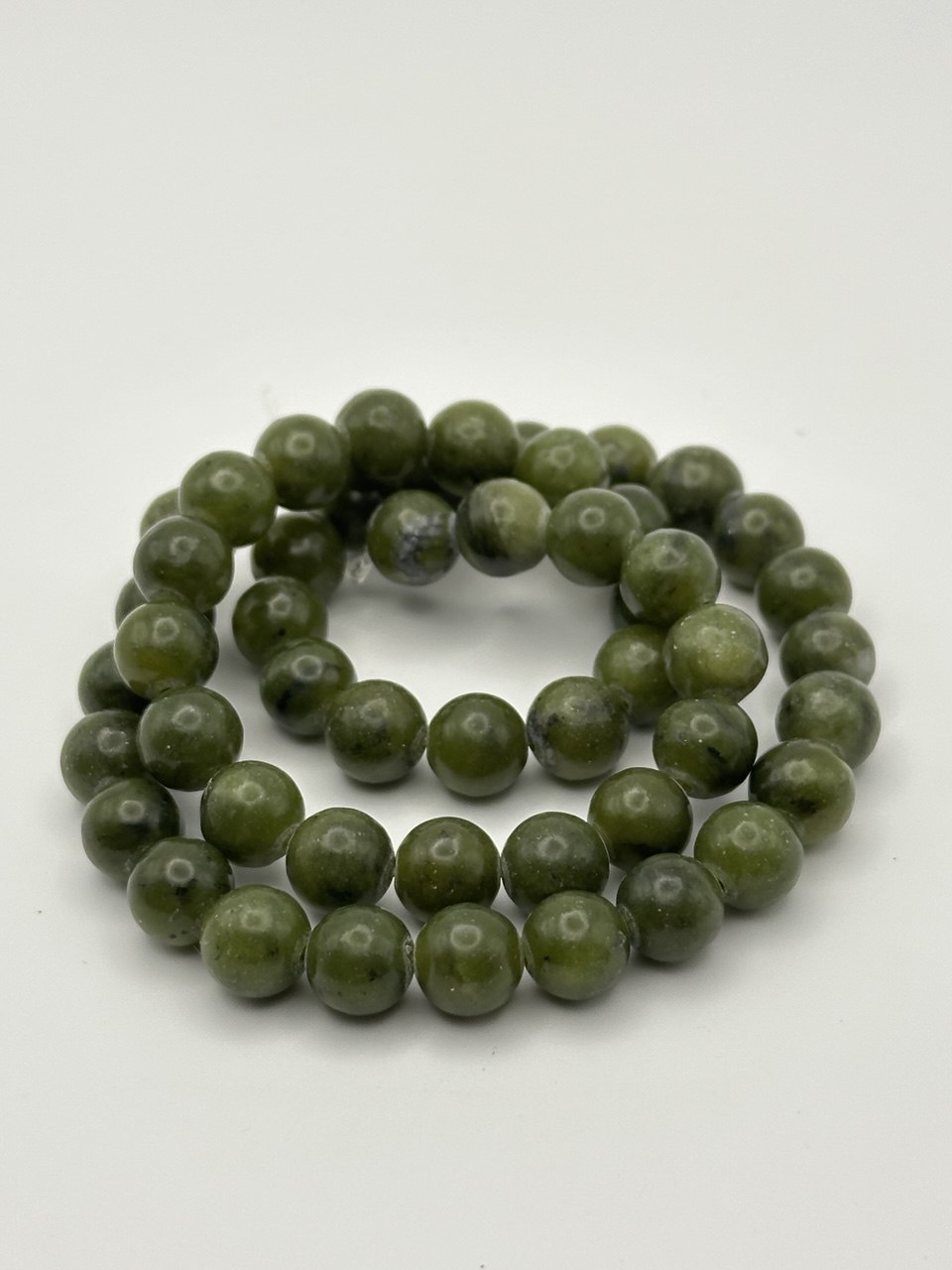 dark green semi-precious round beads on white surface