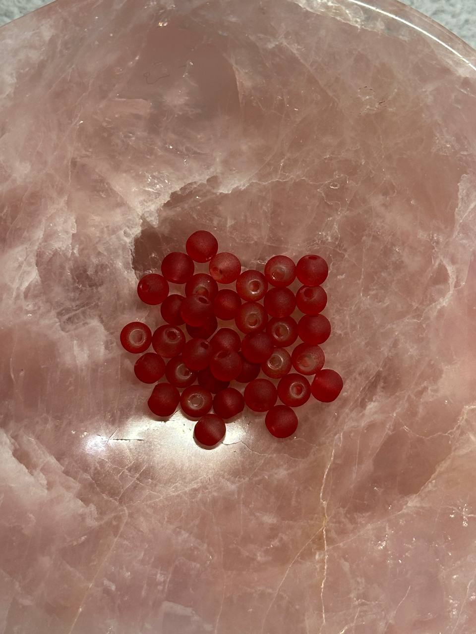 Red beads on a pink marble surface