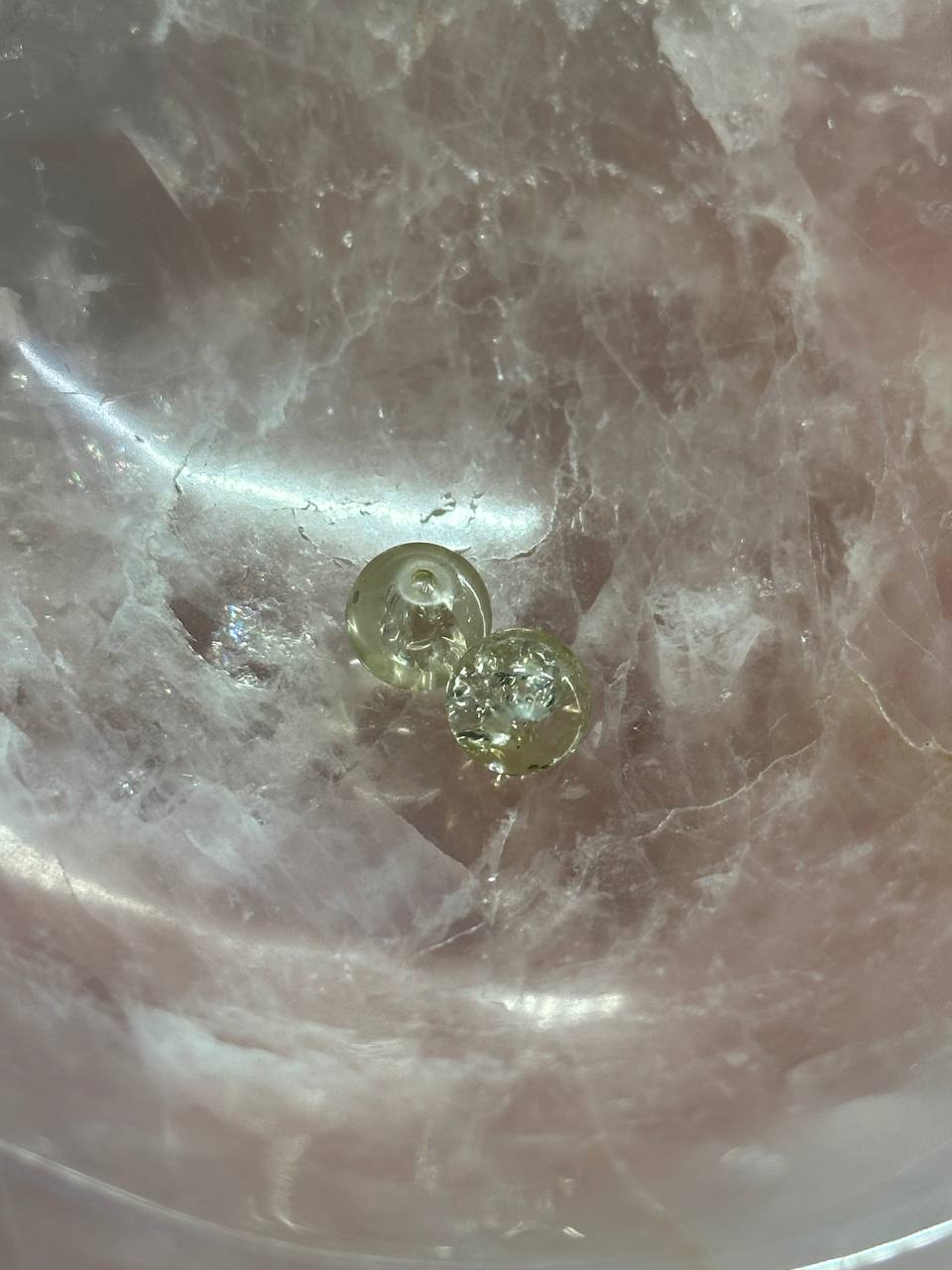 Two small round clear crackle beads on a marbled surface