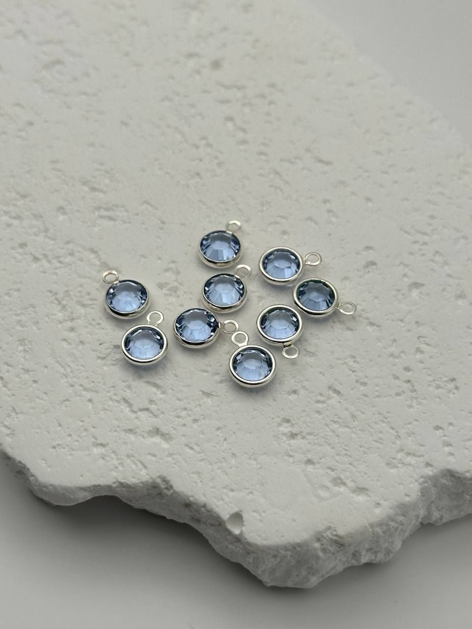 Jewelry connector with aquamarine chatons on a textured stone surface