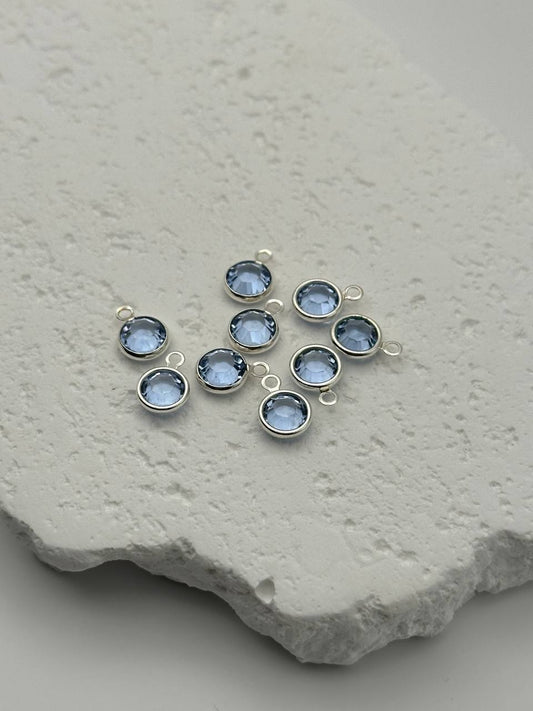 Jewelry connector with aquamarine chatons on a textured stone surface