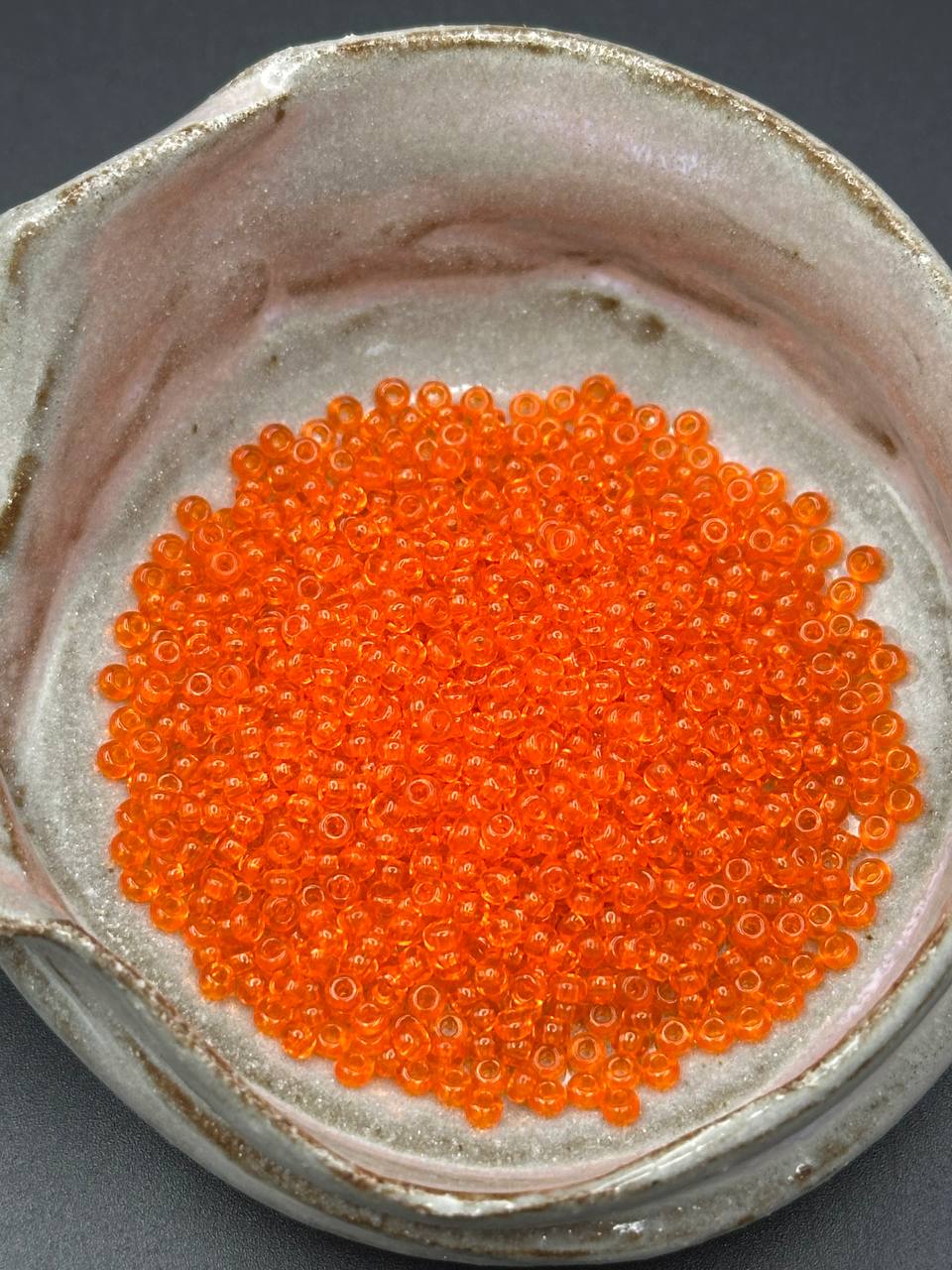 Close-up of orange beads in a ceramic container
