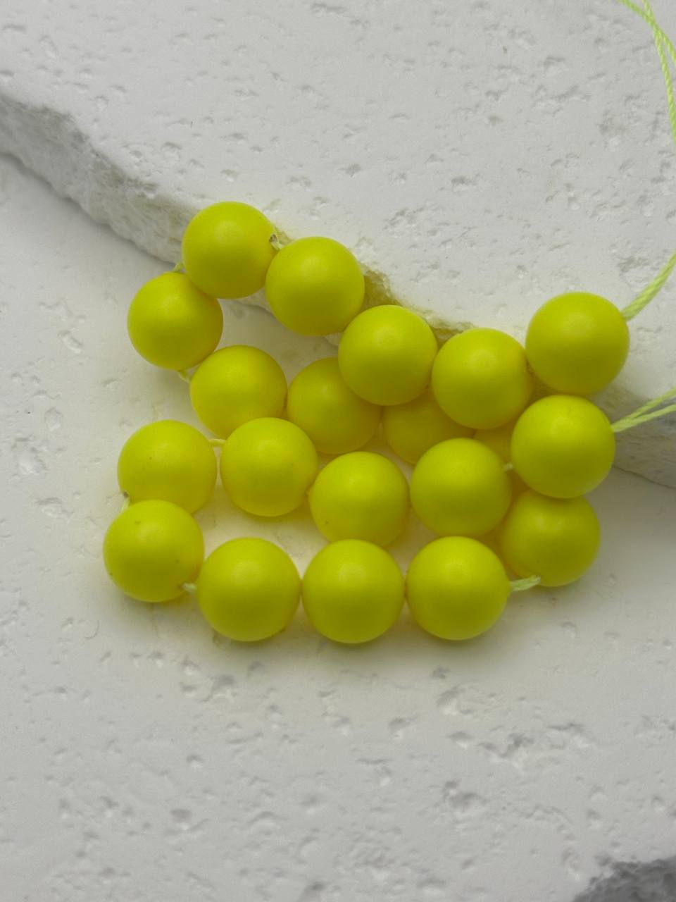 Neon yellow beads on a string against a light gray background