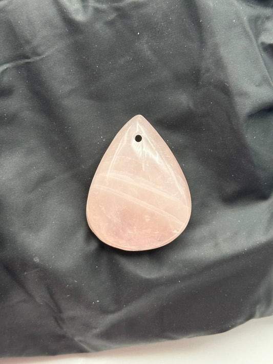 Teardrop-shaped pink stone pendant on a black fabric background