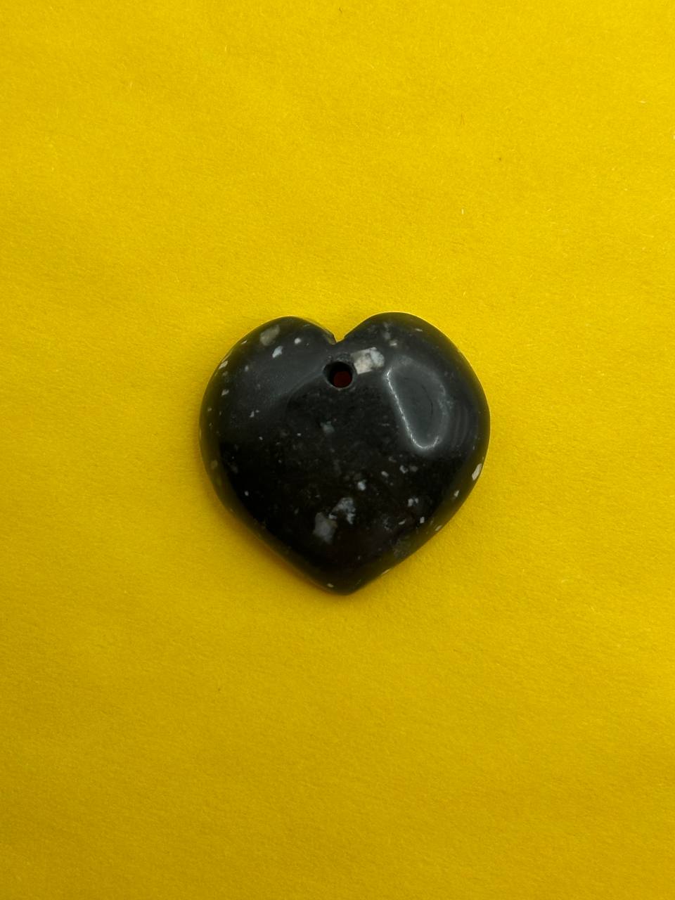 Heart-shaped black stone on a yellow background