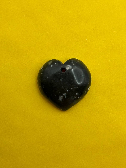 Heart-shaped black stone on a yellow background