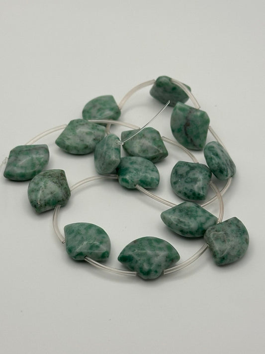 jadeite briolette beads in white and green on white surface