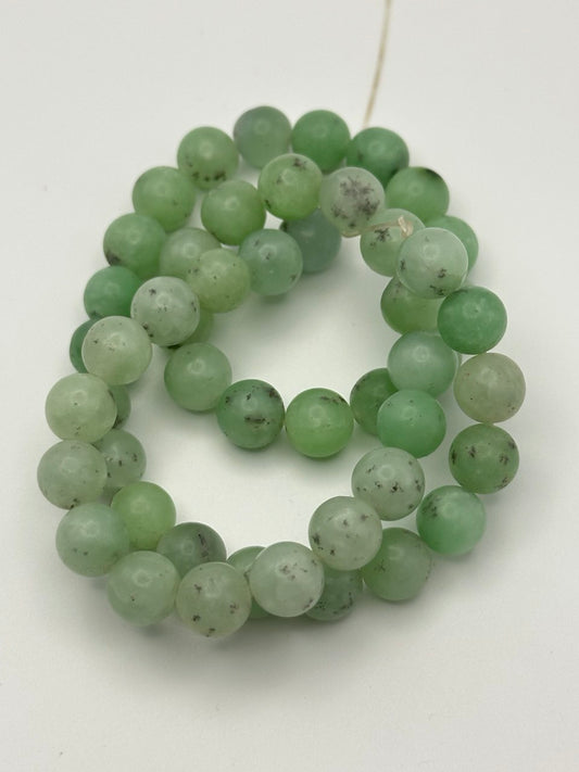 a string of green aventurine beads on a white surface