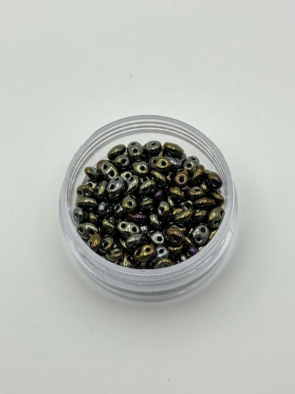 Small container filled with metallic beads on a white background