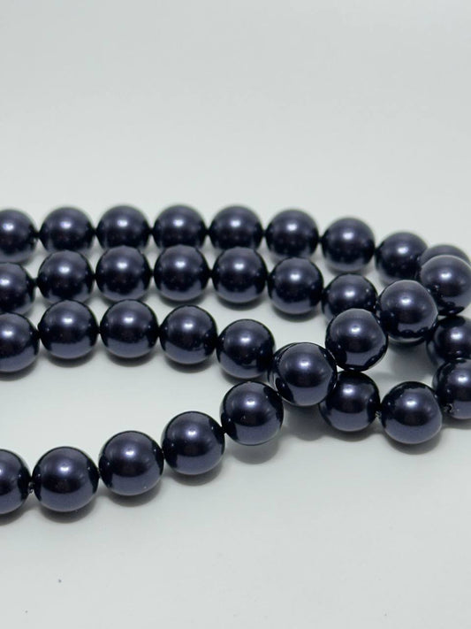 A strand of glossy, dark navy blue round beads arranged in loops on a plain light gray background.