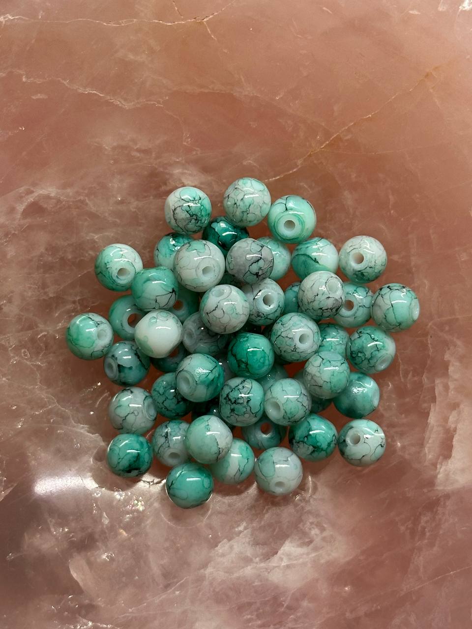 Green and white marbled beads on a marbled surface