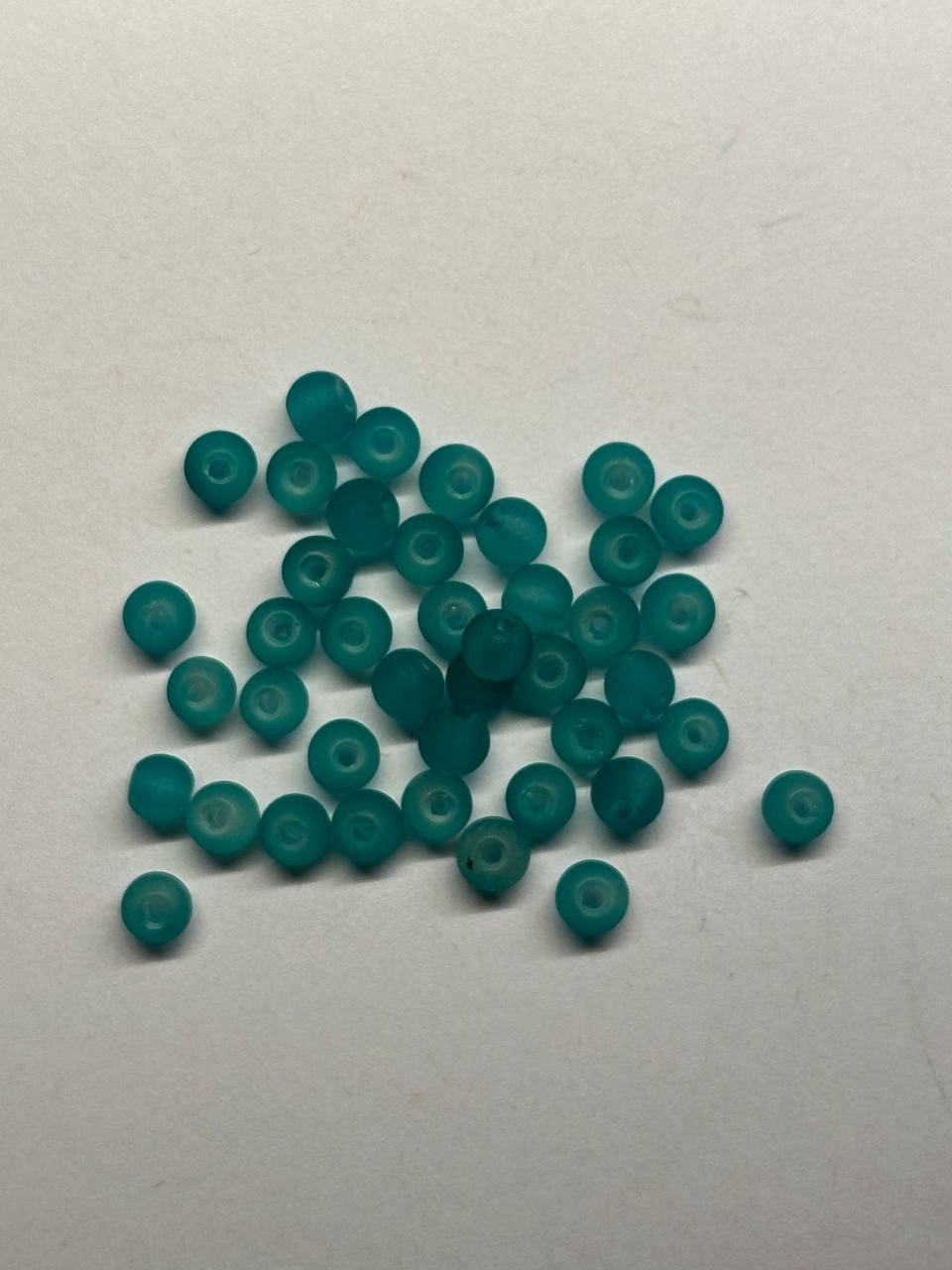 Teal beads scattered on a white background