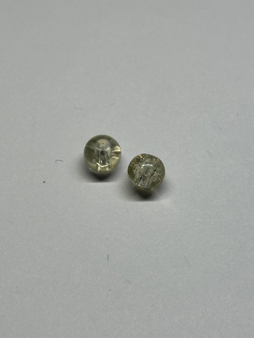 Two small clear crackle beads on a gray background