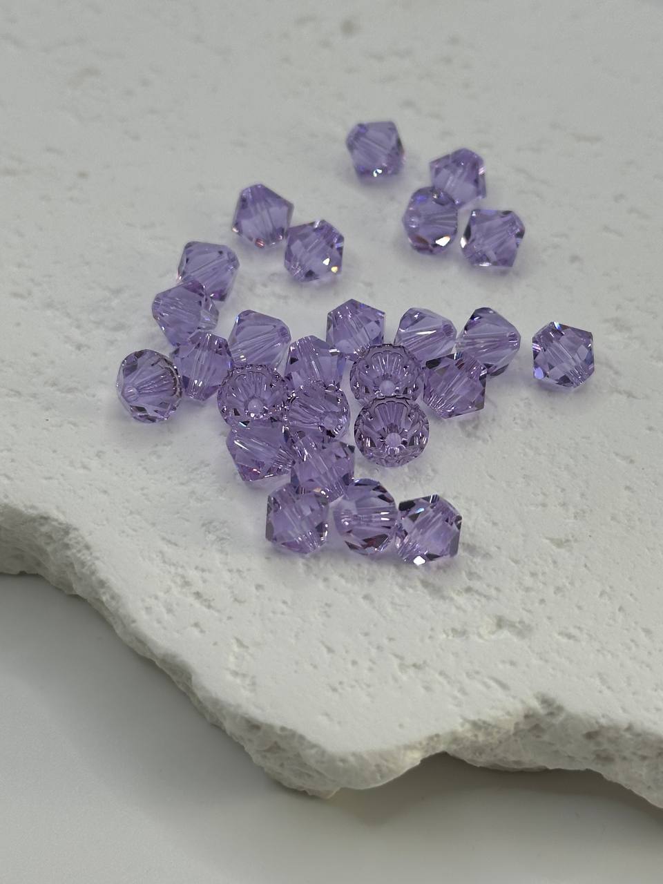 Purple bicone beads on a textured white surface