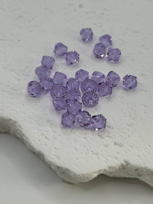 Purple bicone beads on a textured white surface