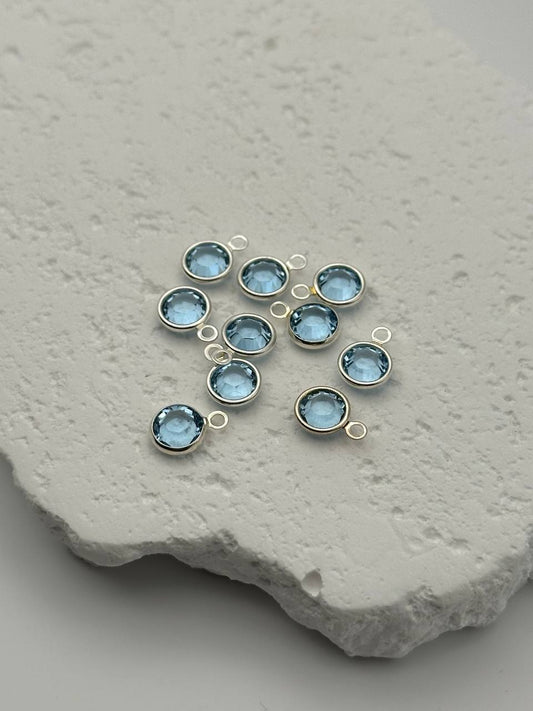 Blue gemstone pendants with silver loops on a textured stone surface