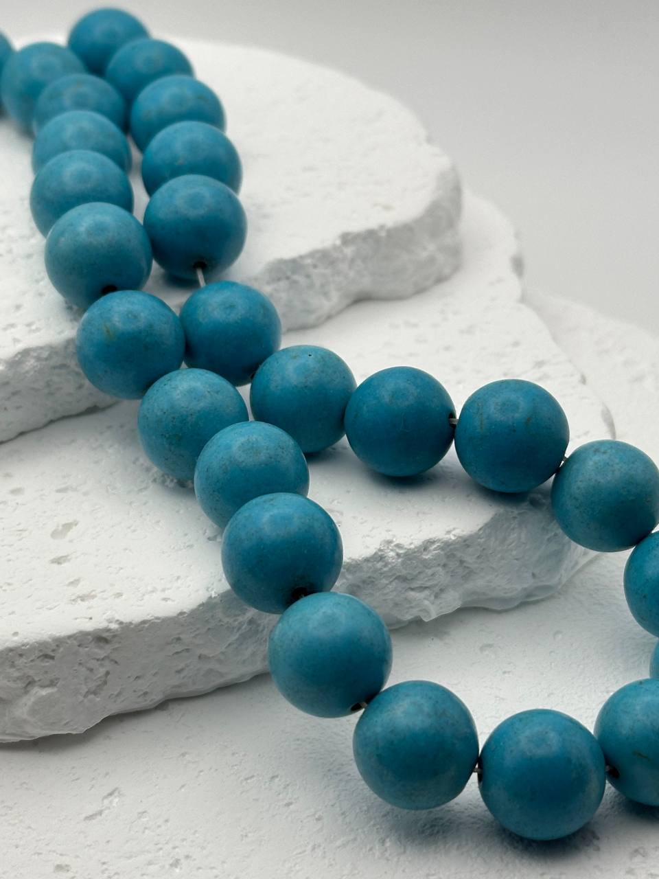 Blue magnesite beads on a textured white surface
