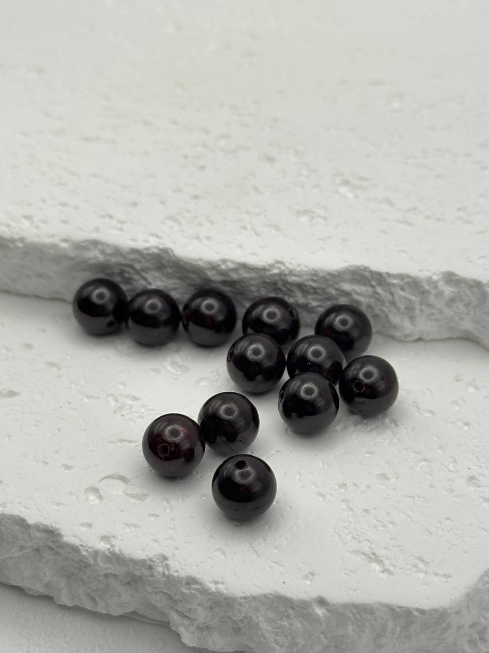 Dark red beads on a textured white surface