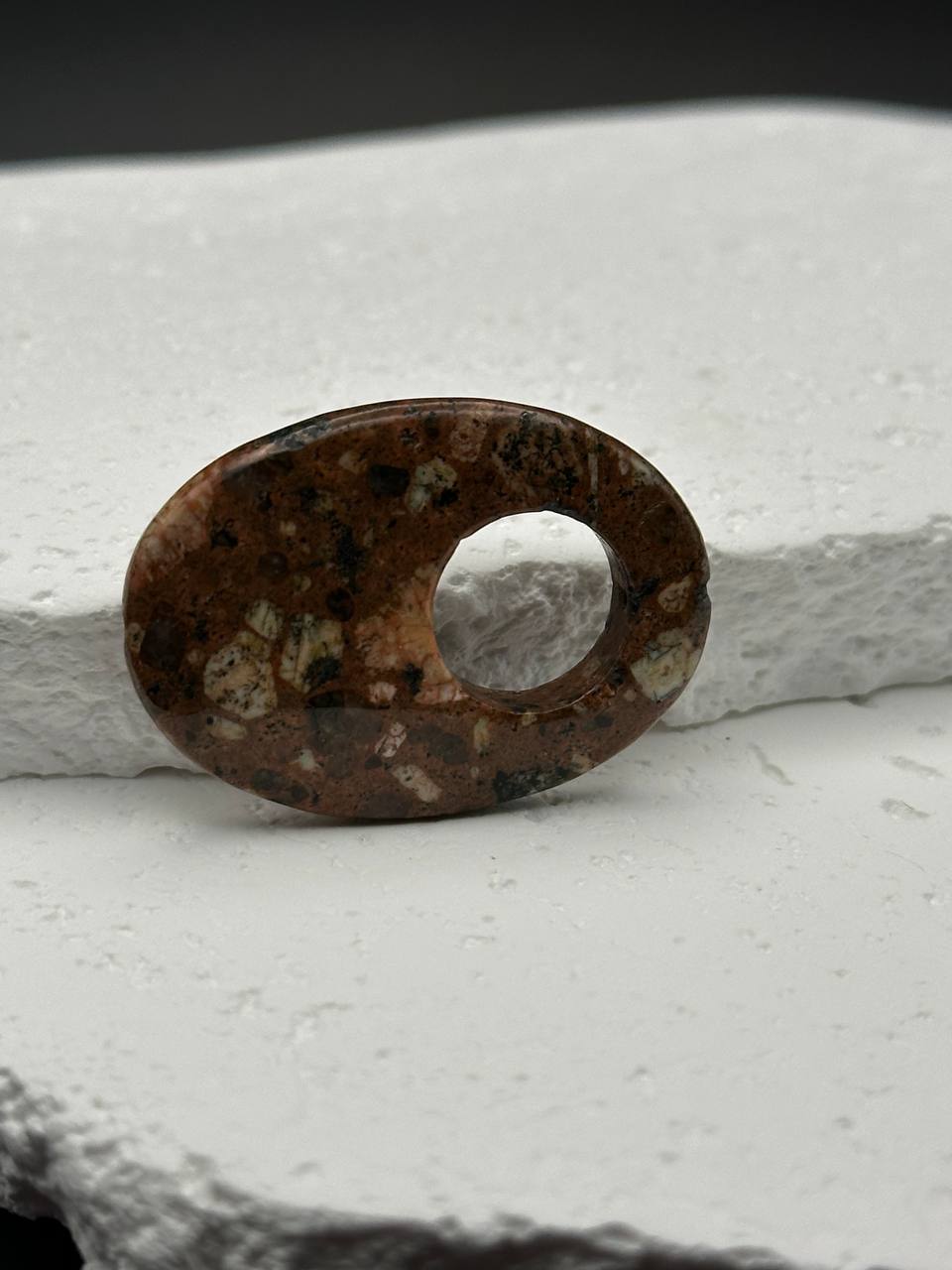 Brown stone with a hole on a white surface
