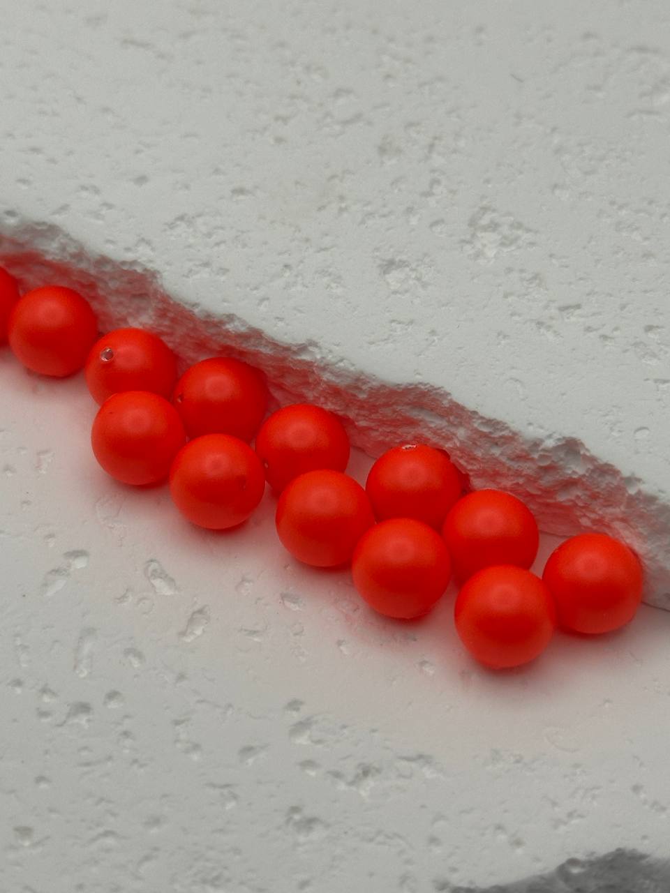 Row of neon red beads on a textured gray surface