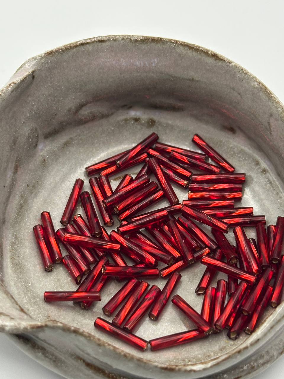 red bugle beads on grey surface