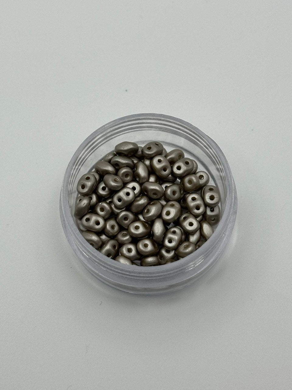 Small container filled with metallic beads on a light gray background