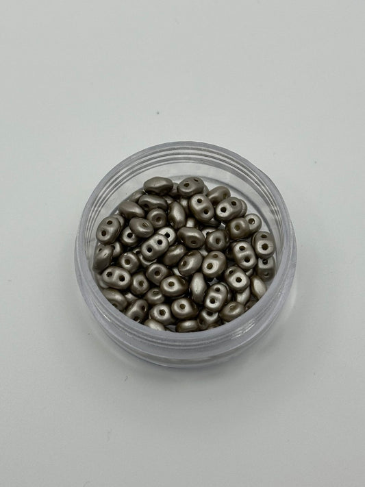 Small container filled with metallic beads on a light gray background