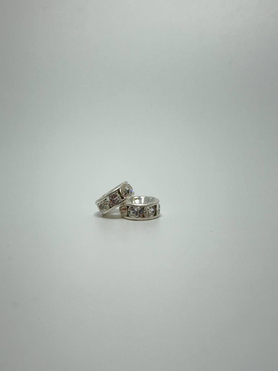 Two silver plated rondelle spacers on white surface