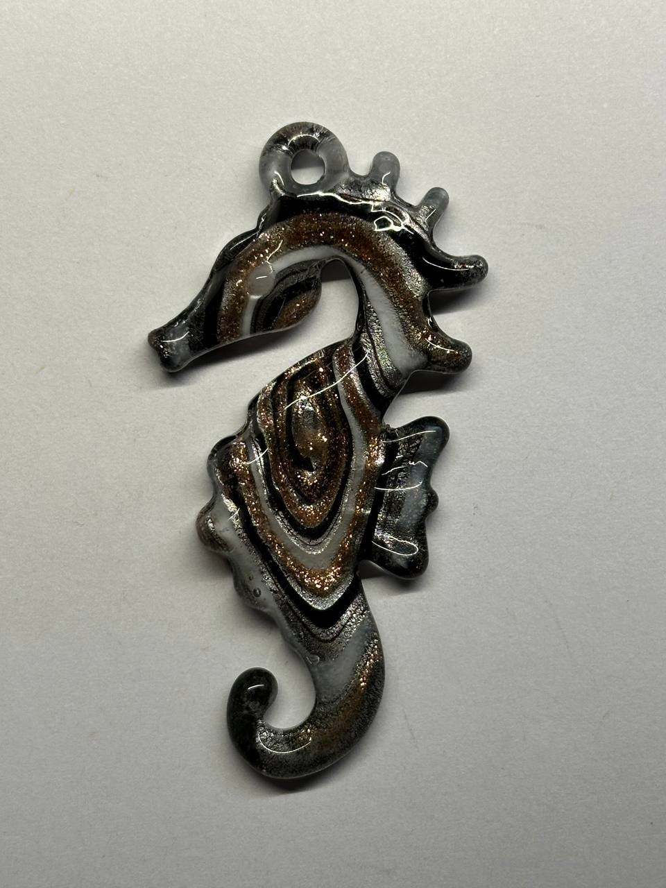 Millefiori seahorse pendant on a light gray background