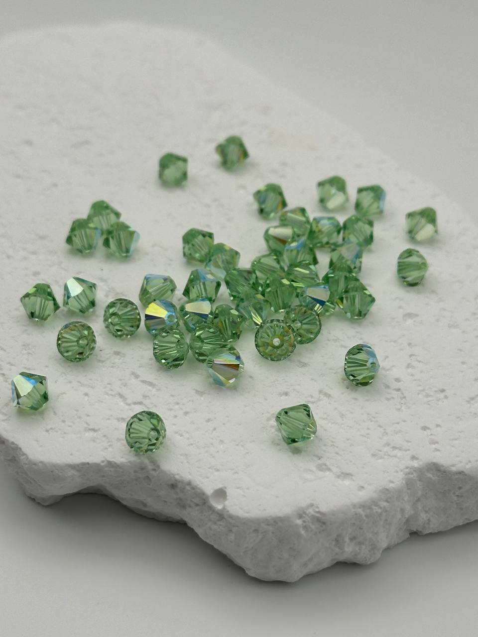 Green bicone beads on a textured white surface