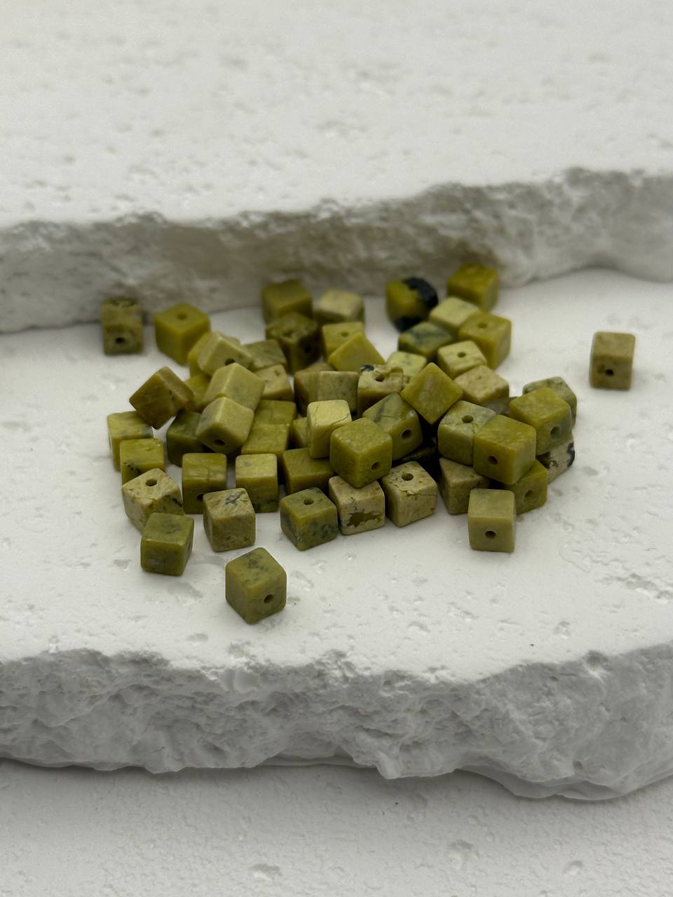 Small green stone cubes on a textured white surface