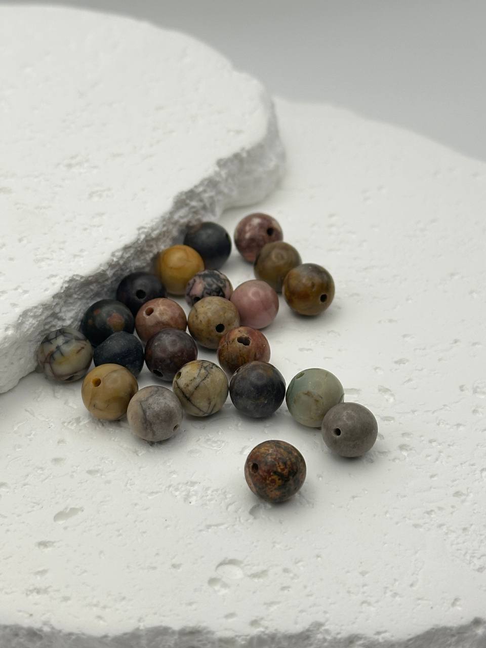 Assorted colored beads on a textured white surface