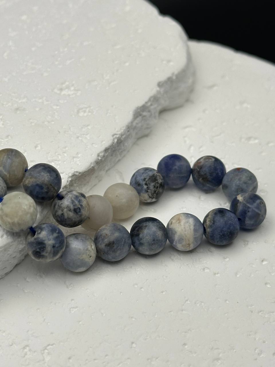 Blue and white sodalite matte beads on white surface
