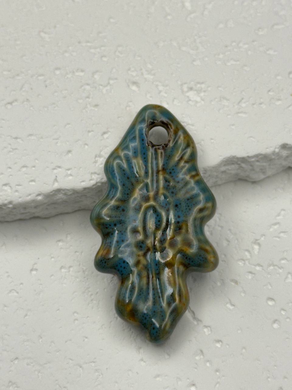 Decorative ceramic tile with blue and green glaze on a white background