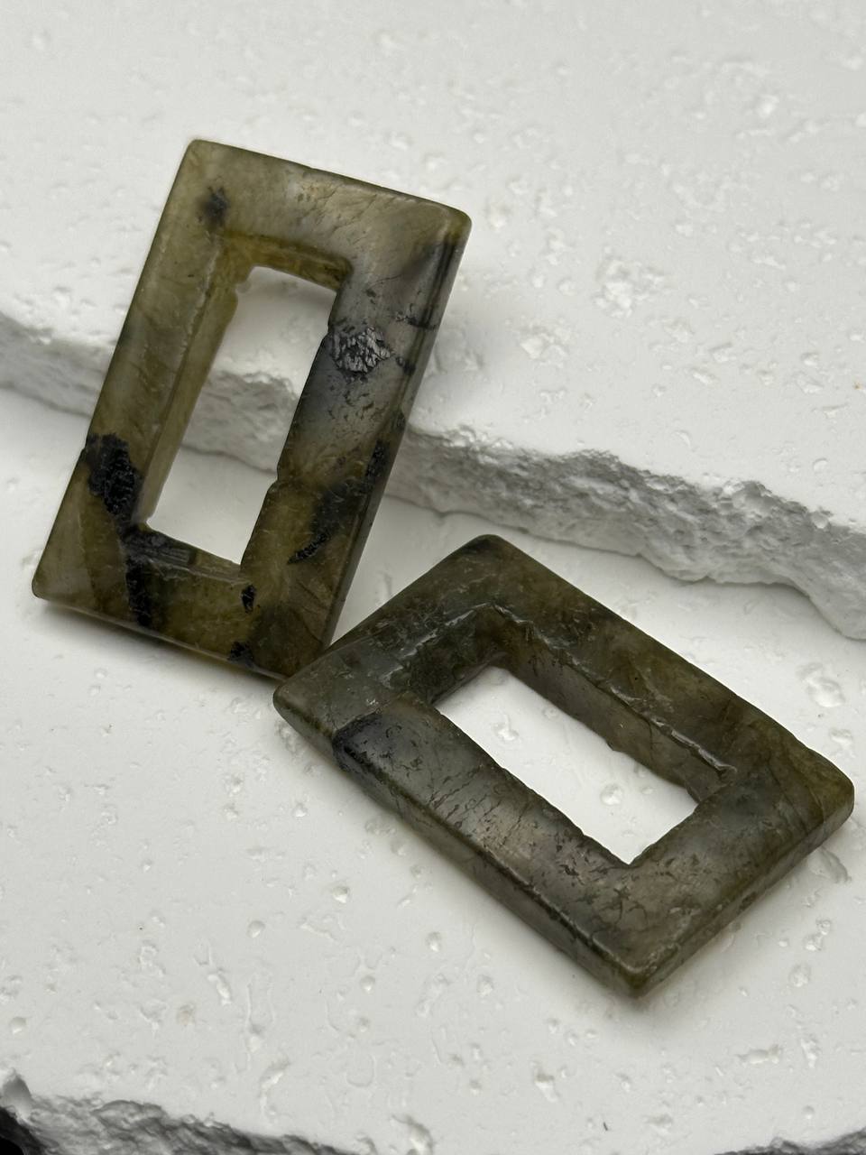 Two rectangular labradorite beads on a textured white surface