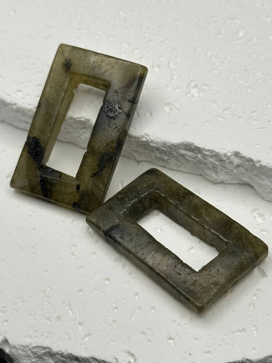 Two rectangular labradorite beads on a textured white surface
