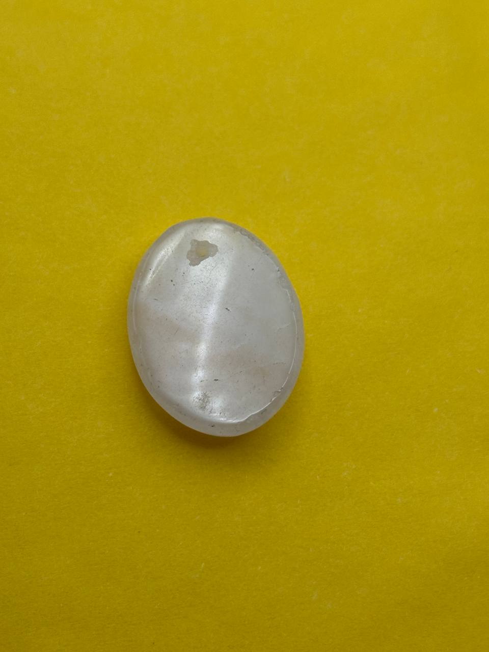 Small white stone with a hole on a yellow background