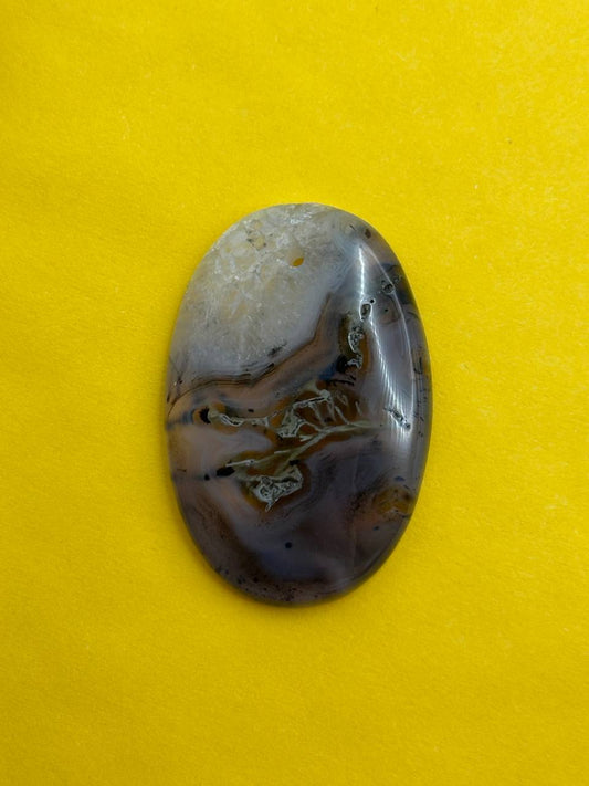 Oval-shaped stone with brown and white patterns on a yellow background