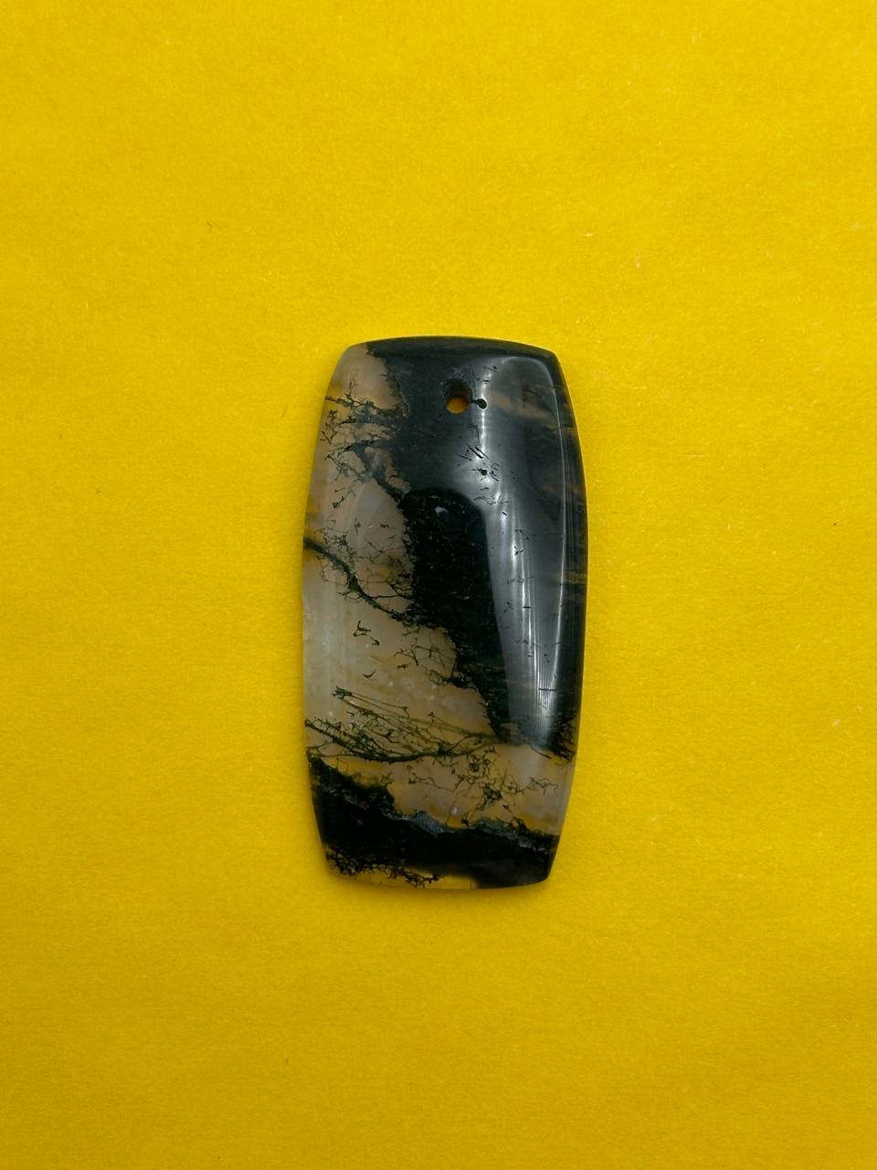 Marbled stone pendant on a yellow background
