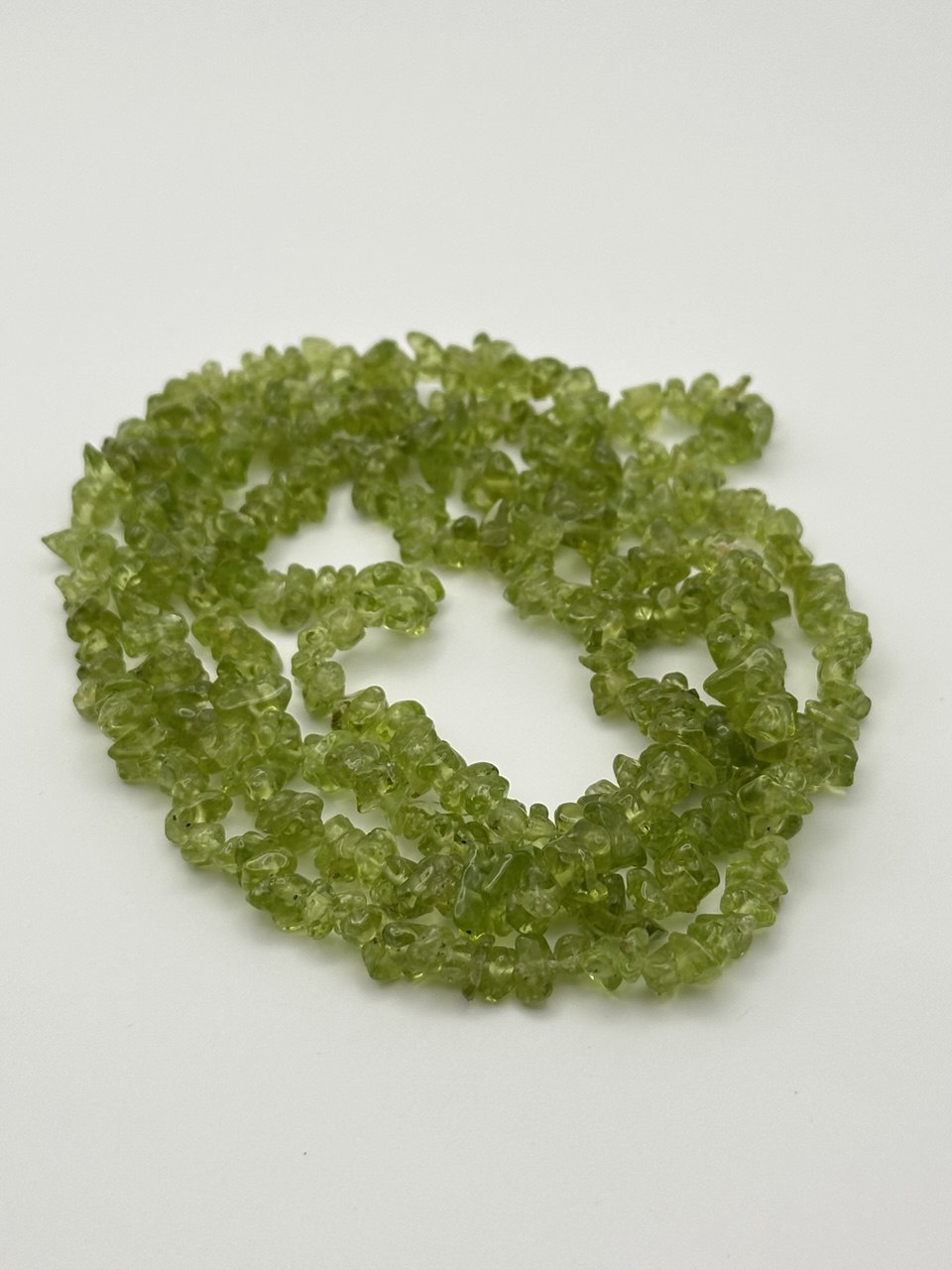Green transparent peridot chips on white surface