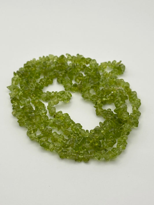 Green transparent peridot chips on white surface