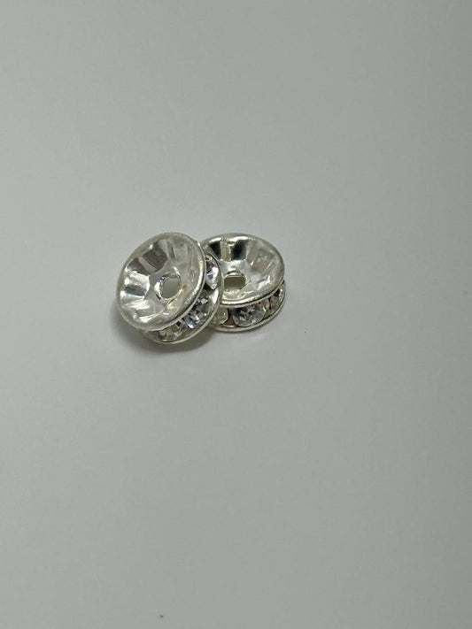 Two silver plated rondelle spacers on white surface